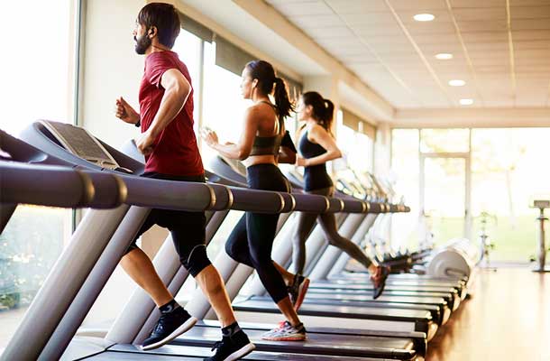 Three people running on treadmills in a health club
