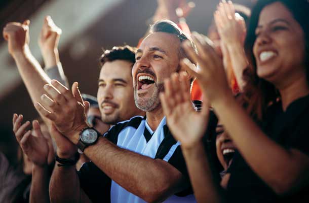 Group of happy spectators at an event clapping and cheering.